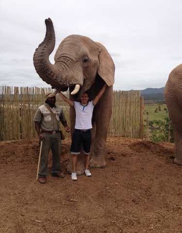Two people posing with an elephant at a wildlife park.
