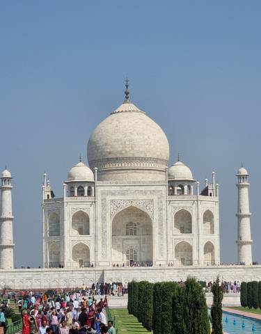 The Taj Mahal with a clear blue sky and tourists below.