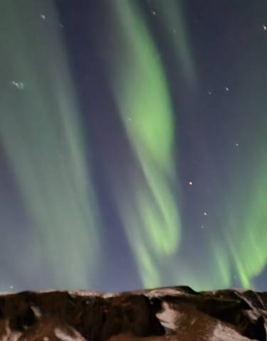 Northern lights over a snow-covered mountain.