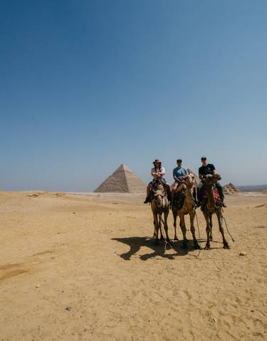 Camel riders in front of a pyramid.