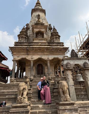 Two people pose in front of a historic temple.