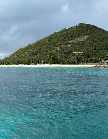 Beach with turquoise water and a hill in the background.