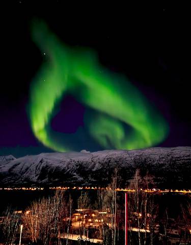 Vibrant green northern lights over a snowy mountain range.