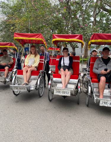 People sitting in red cycle rickshaws on a street.