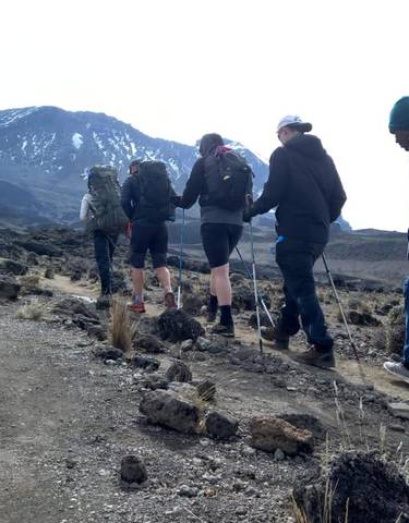 Group of hikers on a trail with snowy mountains.