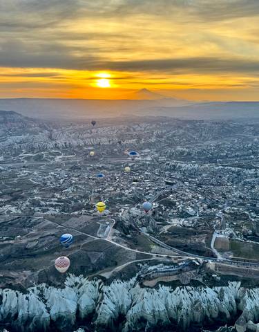 Aerial view of hot air balloons over Cappadocia at dawn.