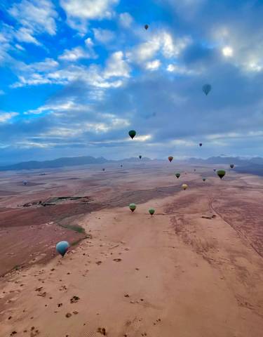 Hot air balloons soaring over a vast desert landscape.