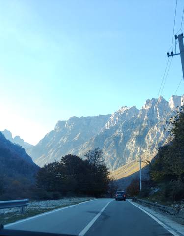 A car driving on a road surrounded by majestic mountains.