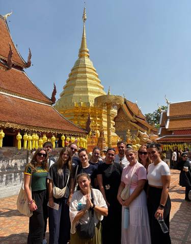 A group of tourists posing in front of a golden temple.