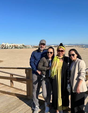 Group of people posing on a beach with a city in the background.