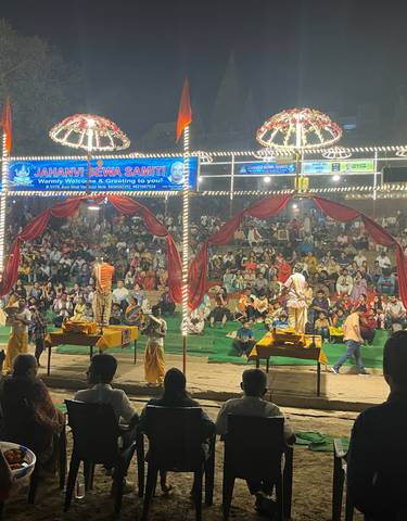 Evening ritual performance on a stage before a large crowd.