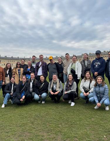 Large group of people posing in front of historic buildings.