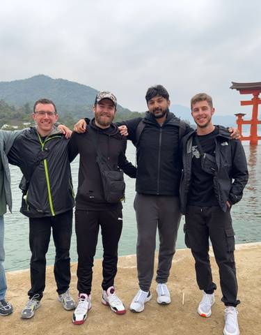 Group of friends posing in front of the Torii gate at Miyajima Island.