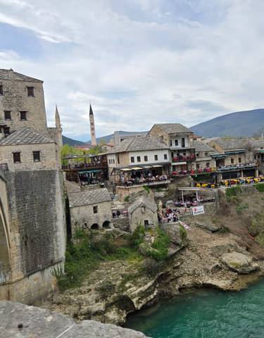Historic bridge and traditional buildings with a scenic river.