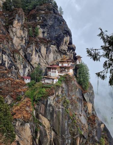 Taktshang Monastery perched on a cliff with fog rolling in.