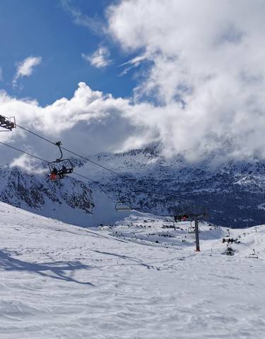 Snowy mountain ski area with ski lifts and cloudy skies.