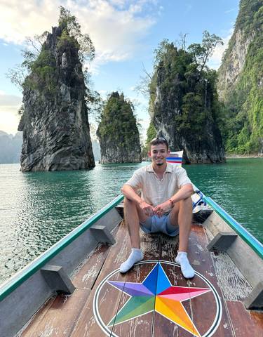 Person sitting on a boat with rock formations in the background.