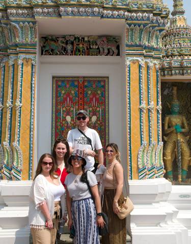 Group of tourists posing in front of a colorful temple.