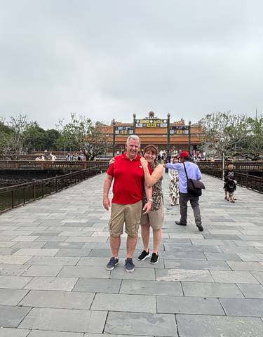 Couple on a bridge in front of a historical building.