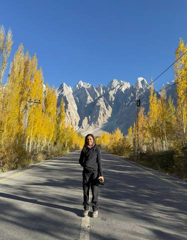 Person standing on a road with a backdrop of tall spiky peaks.