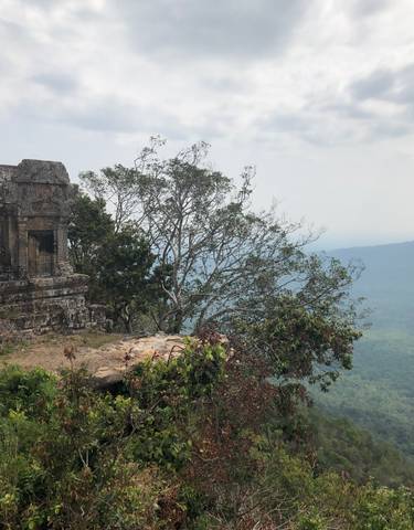 Ruins on a cliff with a view of the valley below.