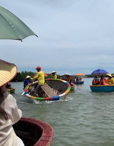 People in traditional hats riding round boats on a river.