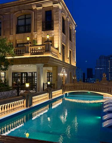 A luxurious hotel rooftop pool at night with city views.