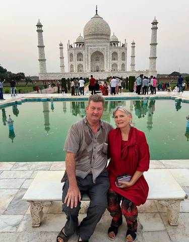 Two people sitting near a reflective pool at the Taj Mahal.