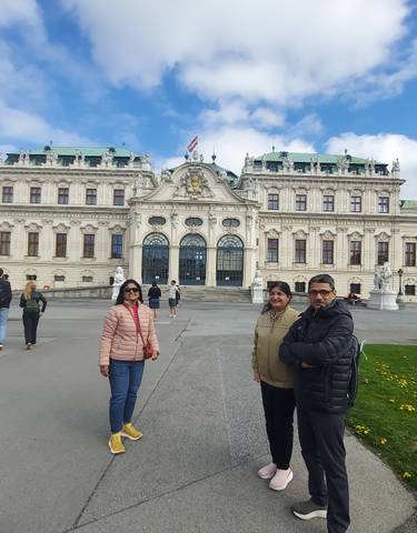 A group of people outside a grand historic palace.
