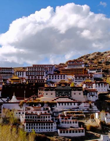 Monasteries built into a mountainside under a blue sky.