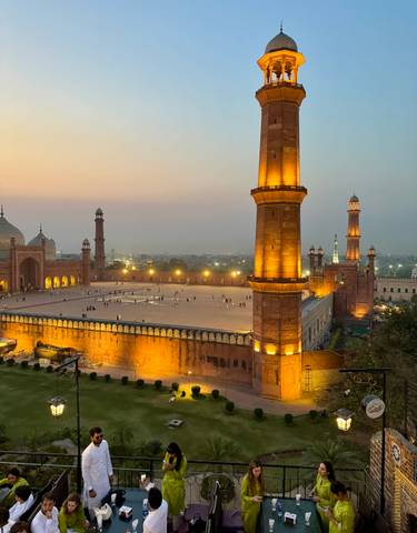 Grand mosque illuminated at dusk, with a courtyard.