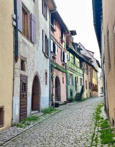 A narrow cobblestone street with pastel-colored buildings.