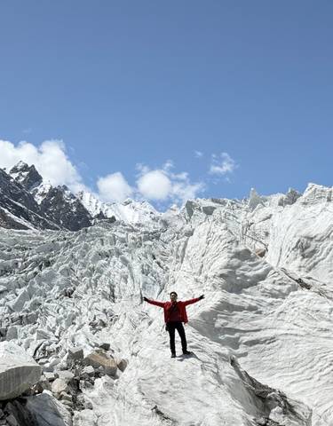 Person with arms raised on a snow-covered glacier.