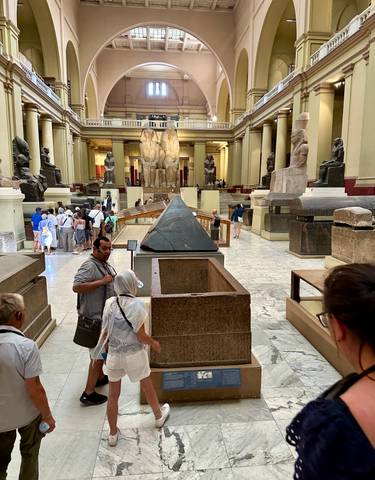 Visitors inside Egyptian museum with large statues.
