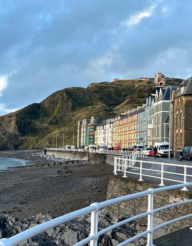 Beachfront view of Aberystwyth with a promenade and colorful buildings.