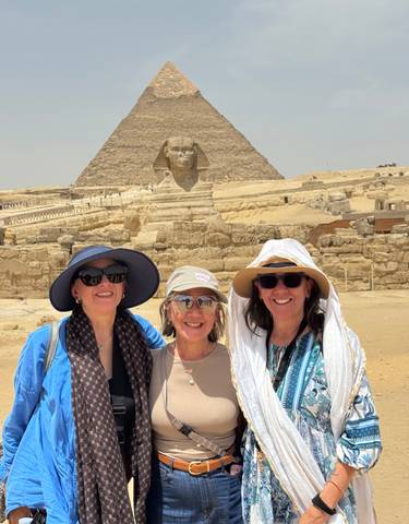 Three women posing in front of the Sphinx and pyramids.