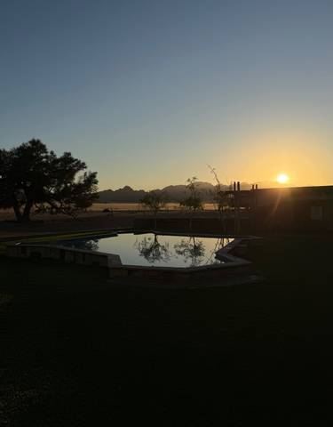 Sunset over a swimming pool with mountains in the background.
