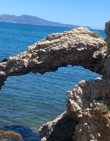 Rock formation arch by the blue sea.