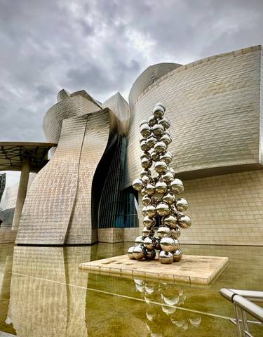 The Guggenheim Museum in Bilbao with reflective sculptures outside.