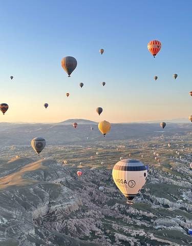Hot air balloons over Cappadocia's landscape during sunrise.