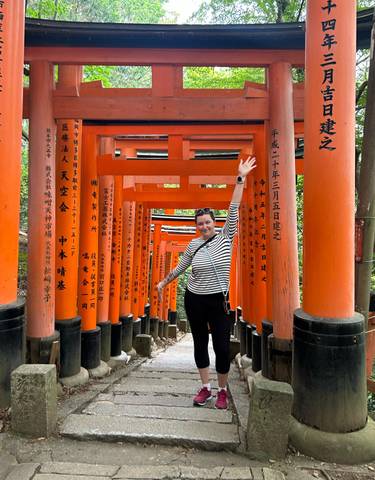 Person standing among traditional orange torii gates.
