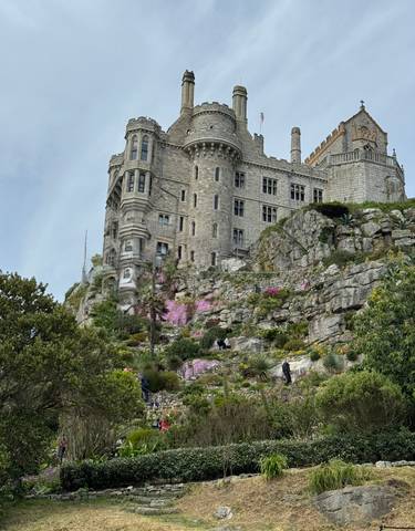 A magnificent castle built on a rocky hill with gardens below.