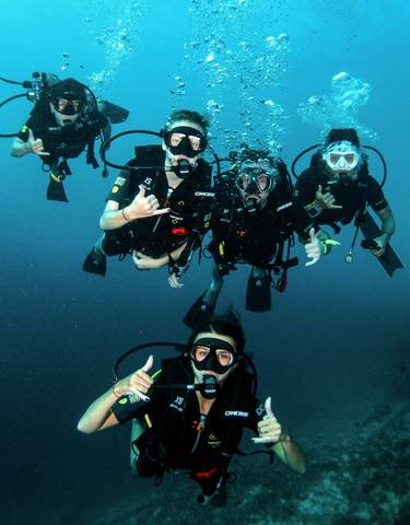 Group of scuba divers underwater in clear blue waters.