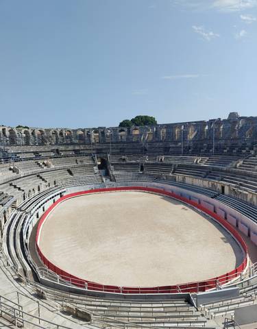 Amphitheater with tiered seating and a sandy arena.