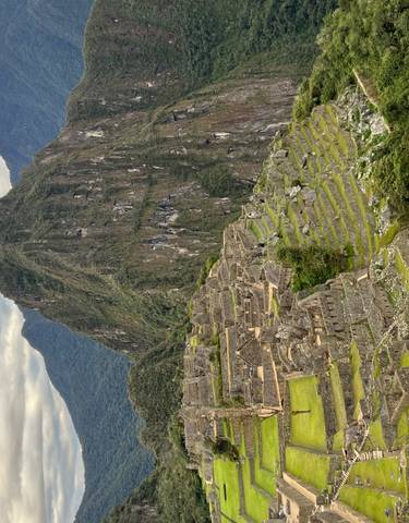 View of Machu Picchu with terraces and high peak.