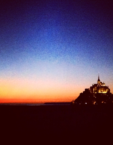 Scenic view of Mont Saint-Michel at sunset, beautifully silhouetted against the sky.