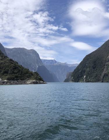 Fjord landscape with steep cliffs and a blue sky.