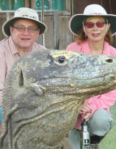 Two people posing with a Komodo dragon.