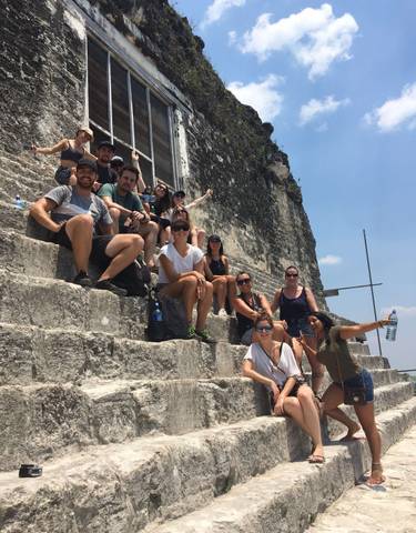 Group of people sitting on ancient stone steps.