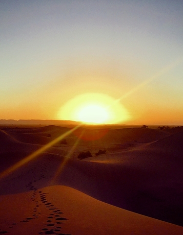 Sun setting over desert dunes.